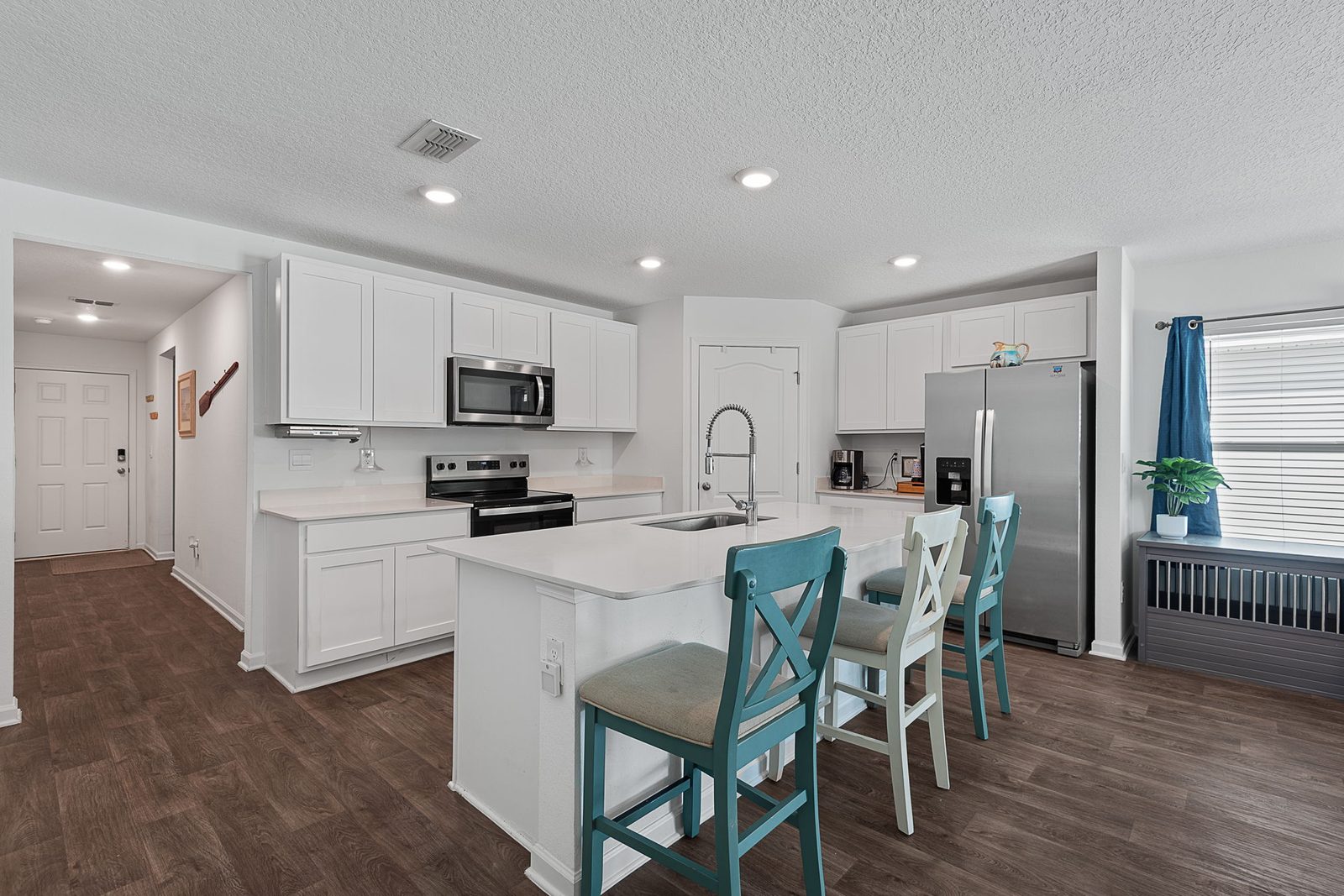 Bright quartz kitchen with stainless appliances and a large center island